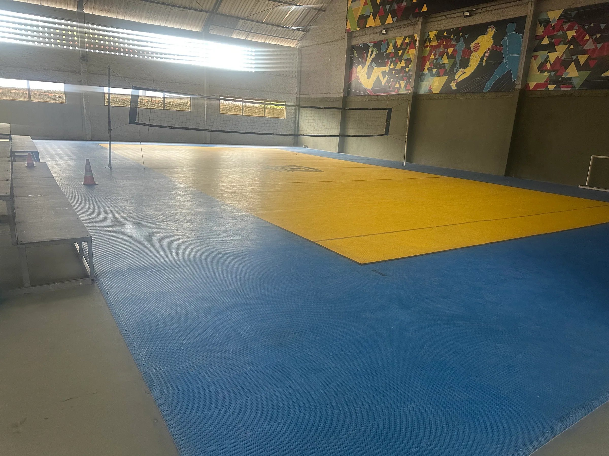 Quadra de vôlei coberta vista pela lateral, com rede montada
