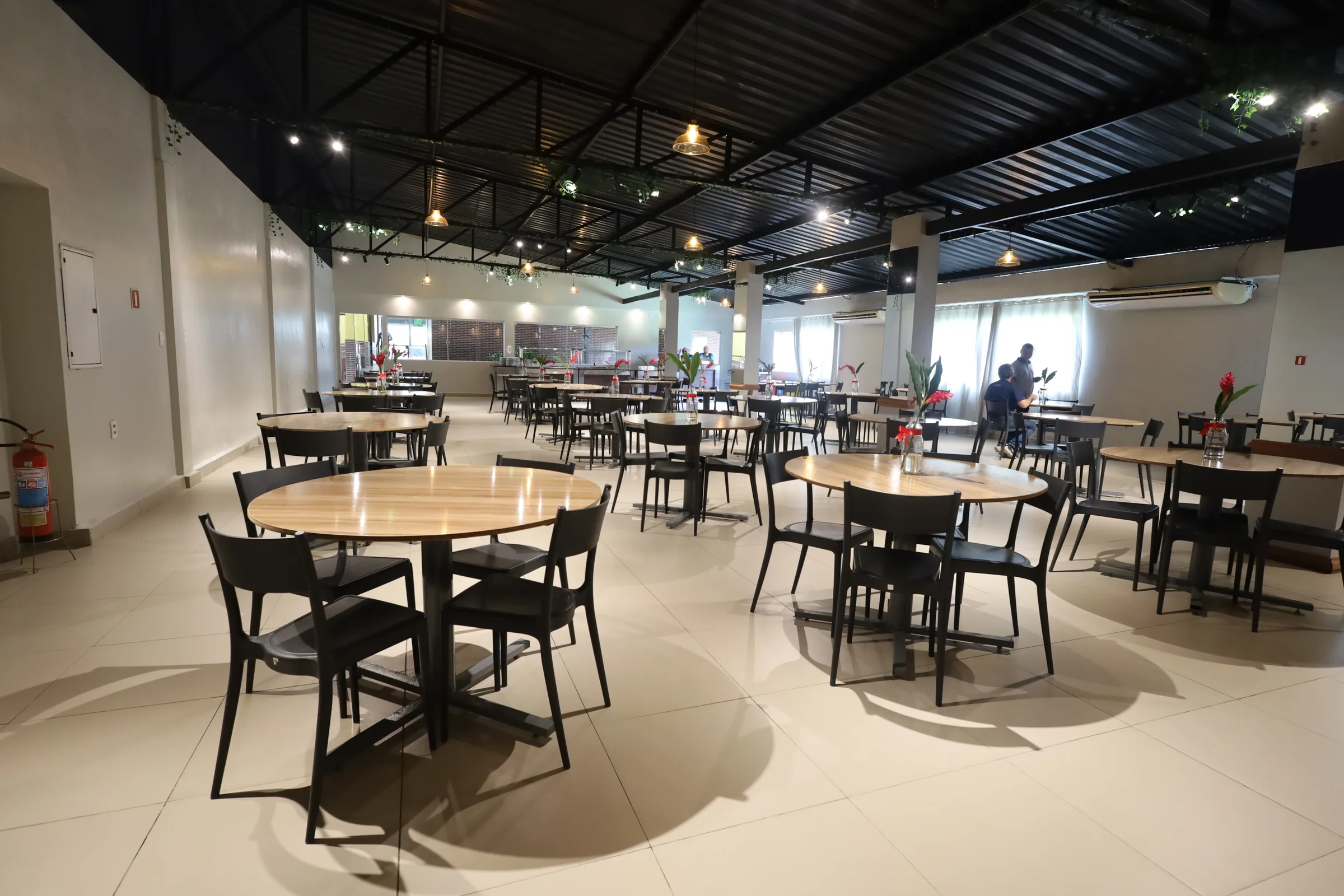 Refeitório com mesas e área de apoio ao fundo
