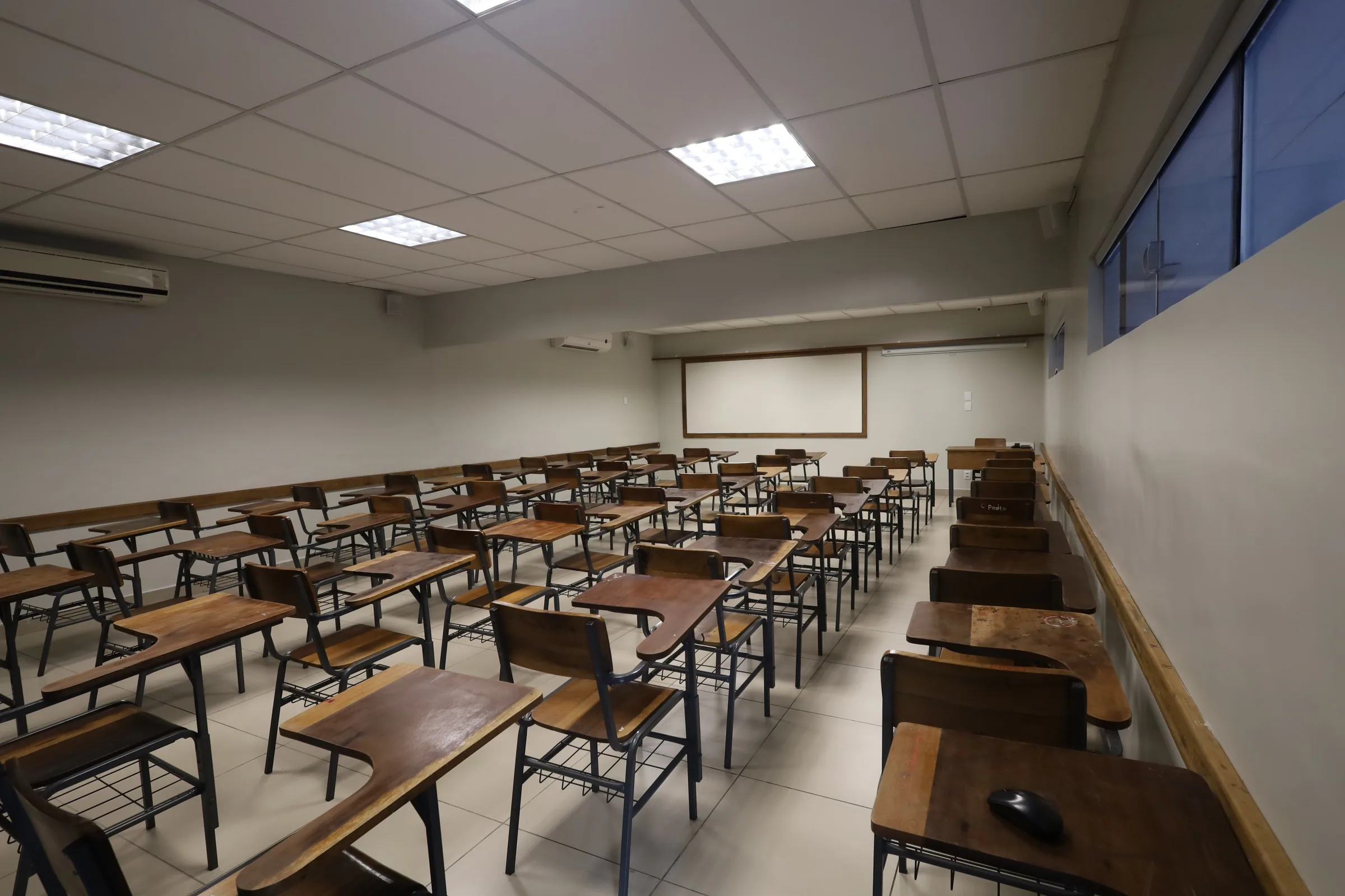 Sala de aula com carteiras organizadas em fileiras diante do quadro